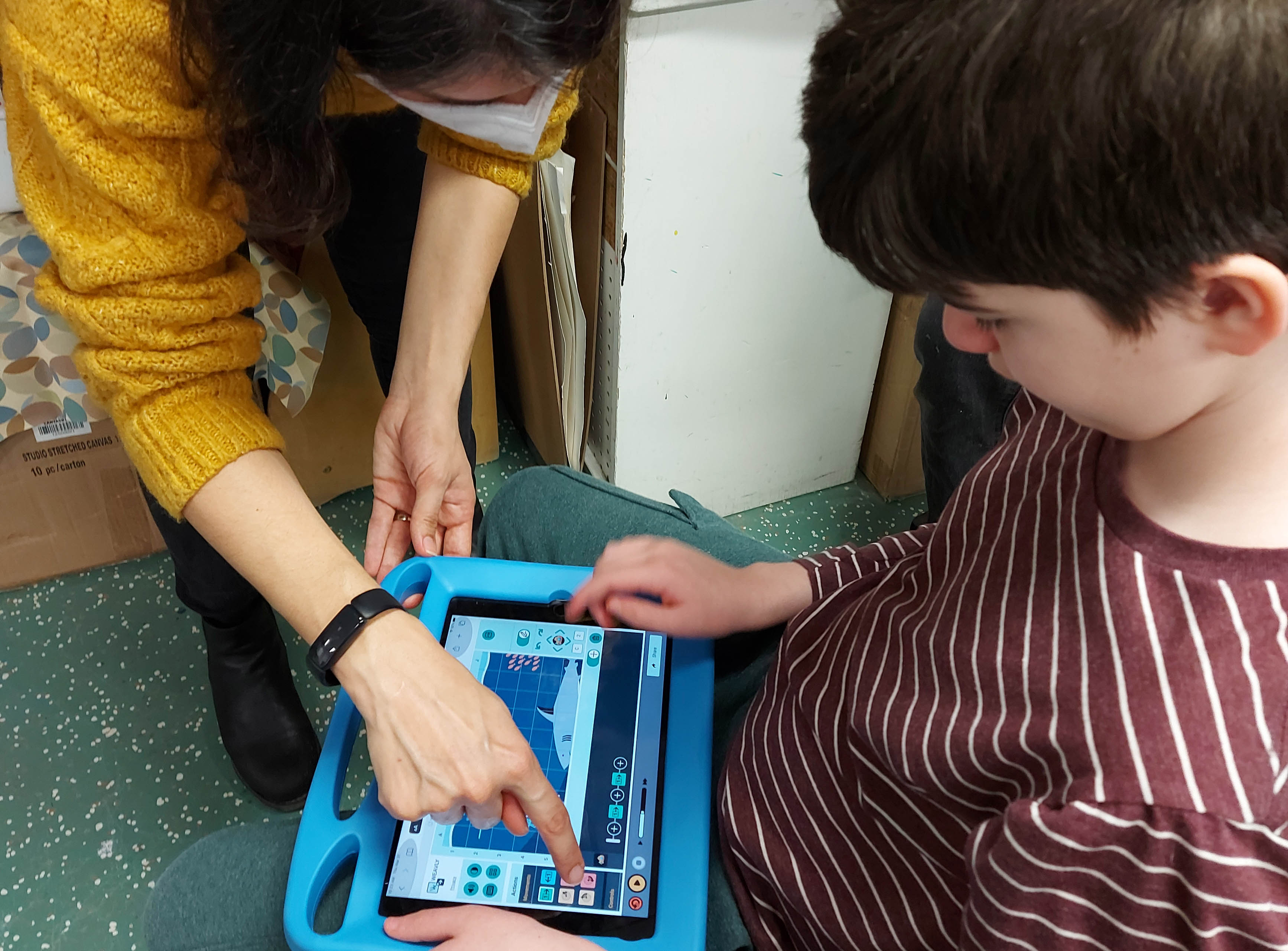 Sharing back new updates on the Weavly coding environment with kids Facilitator showing new items on the Weavly coding environment to a child